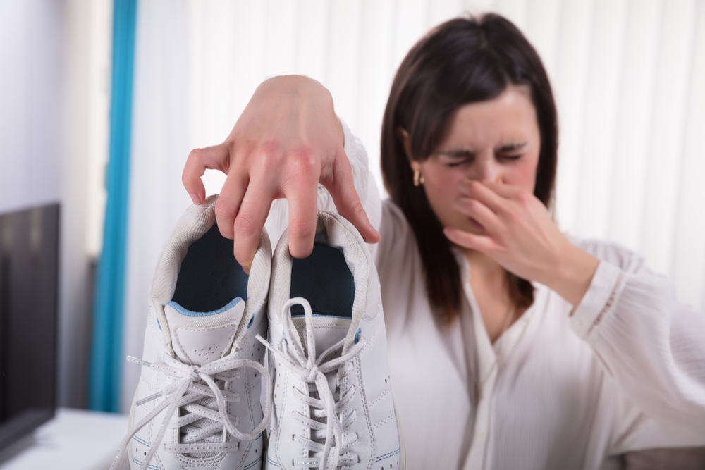 Woman Holding Dirty Stinky Shoes