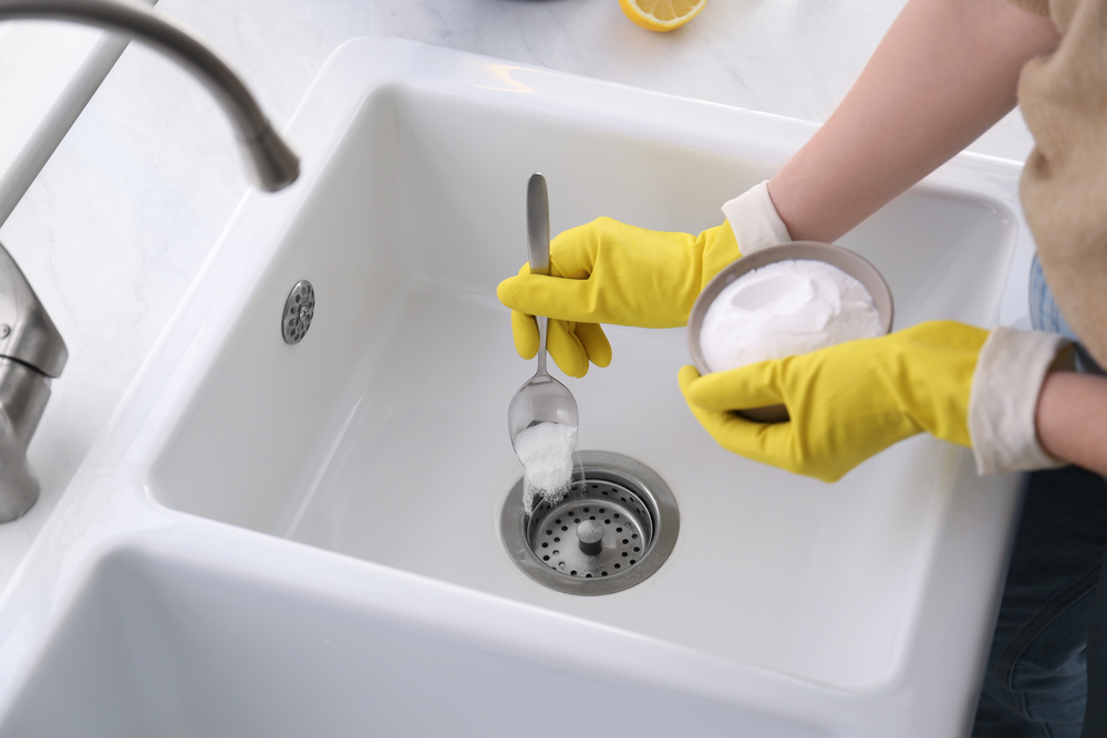 Woman using baking soda to unclog sink