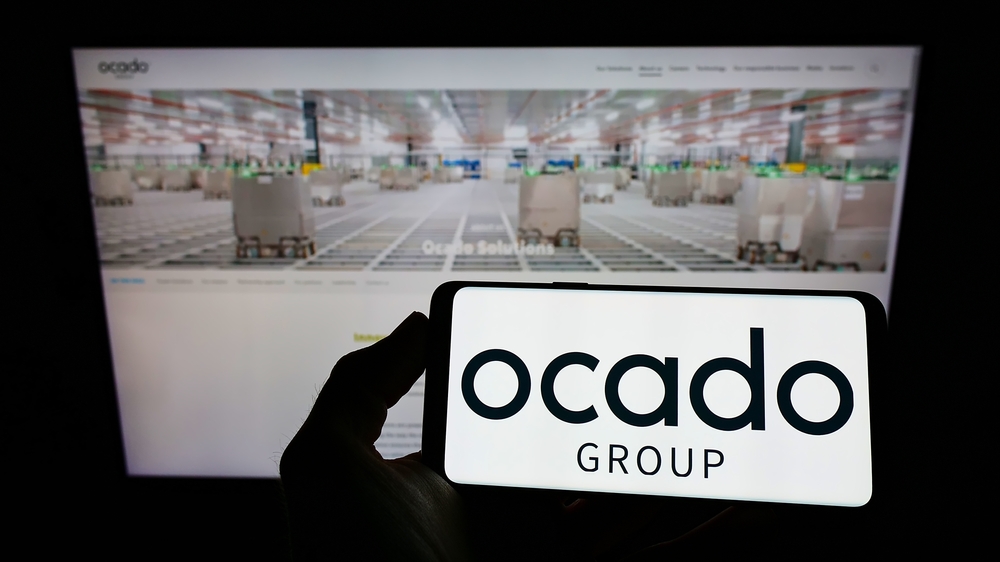 Person holding cellphone with logo of British retail company Ocado Group