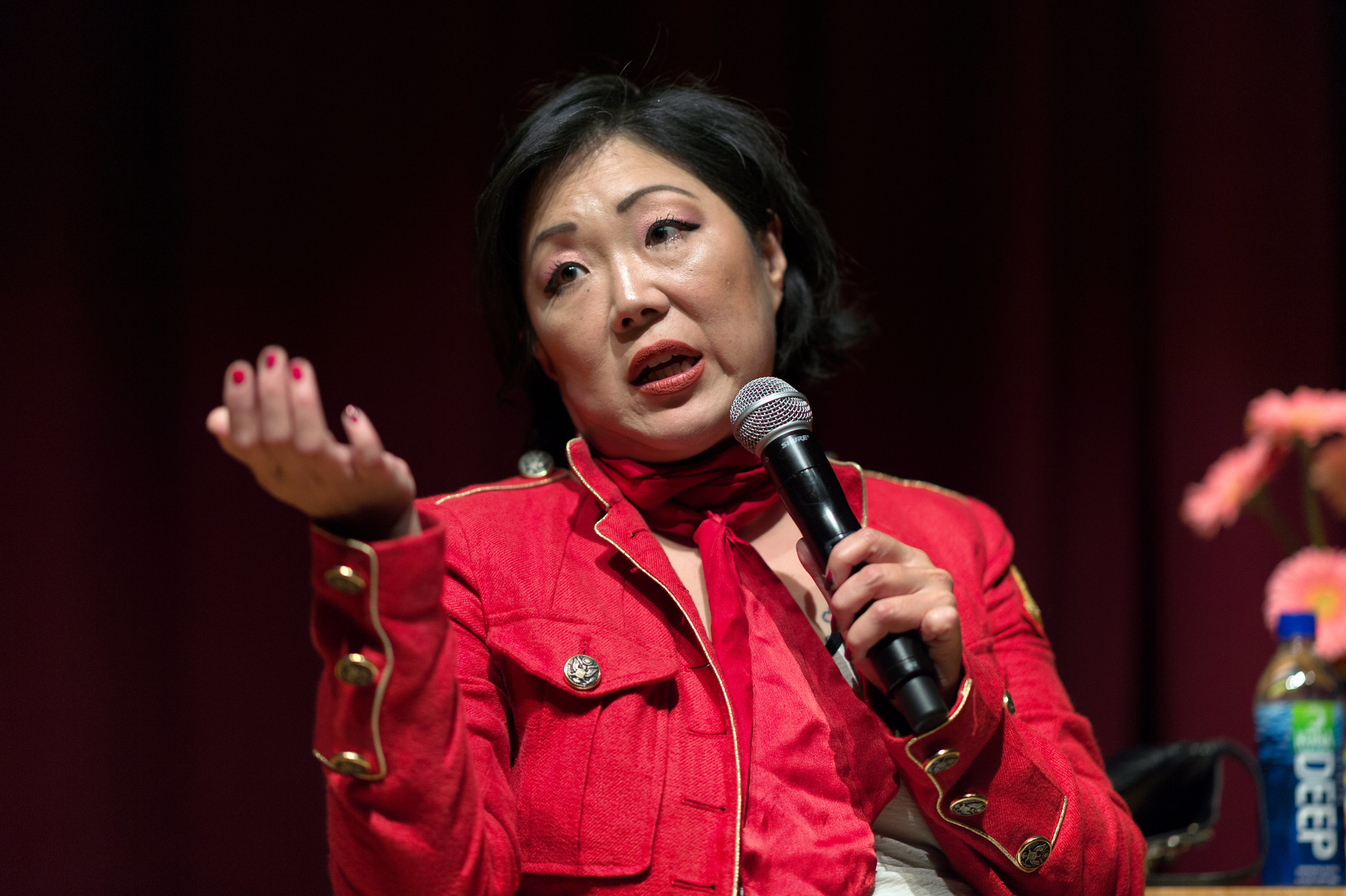 Margaret Cho in red jacket is talking.