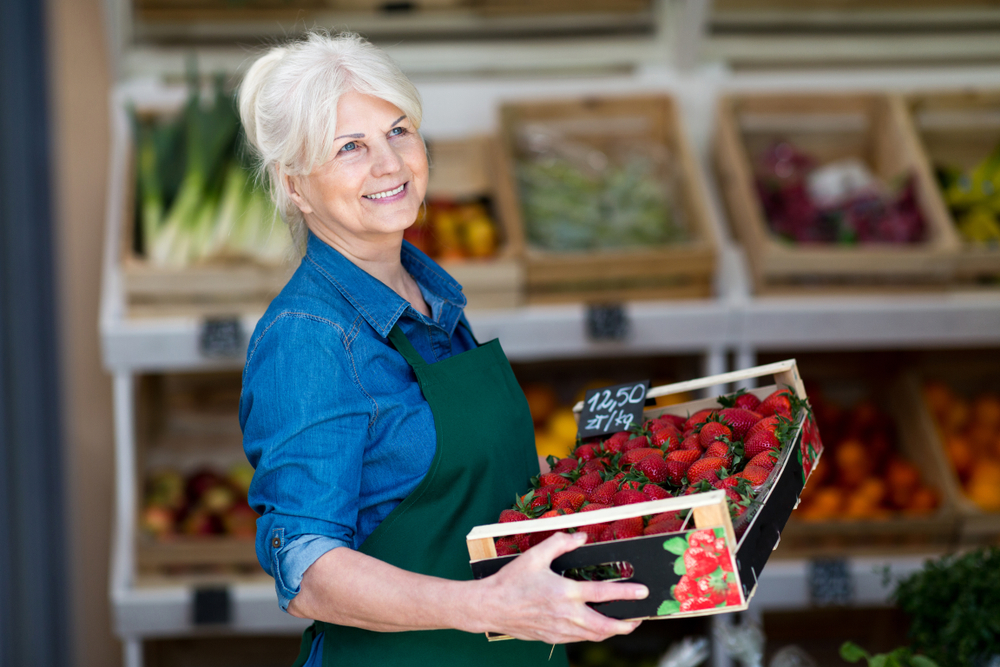 Shop assistant holding box with fresh strawberries