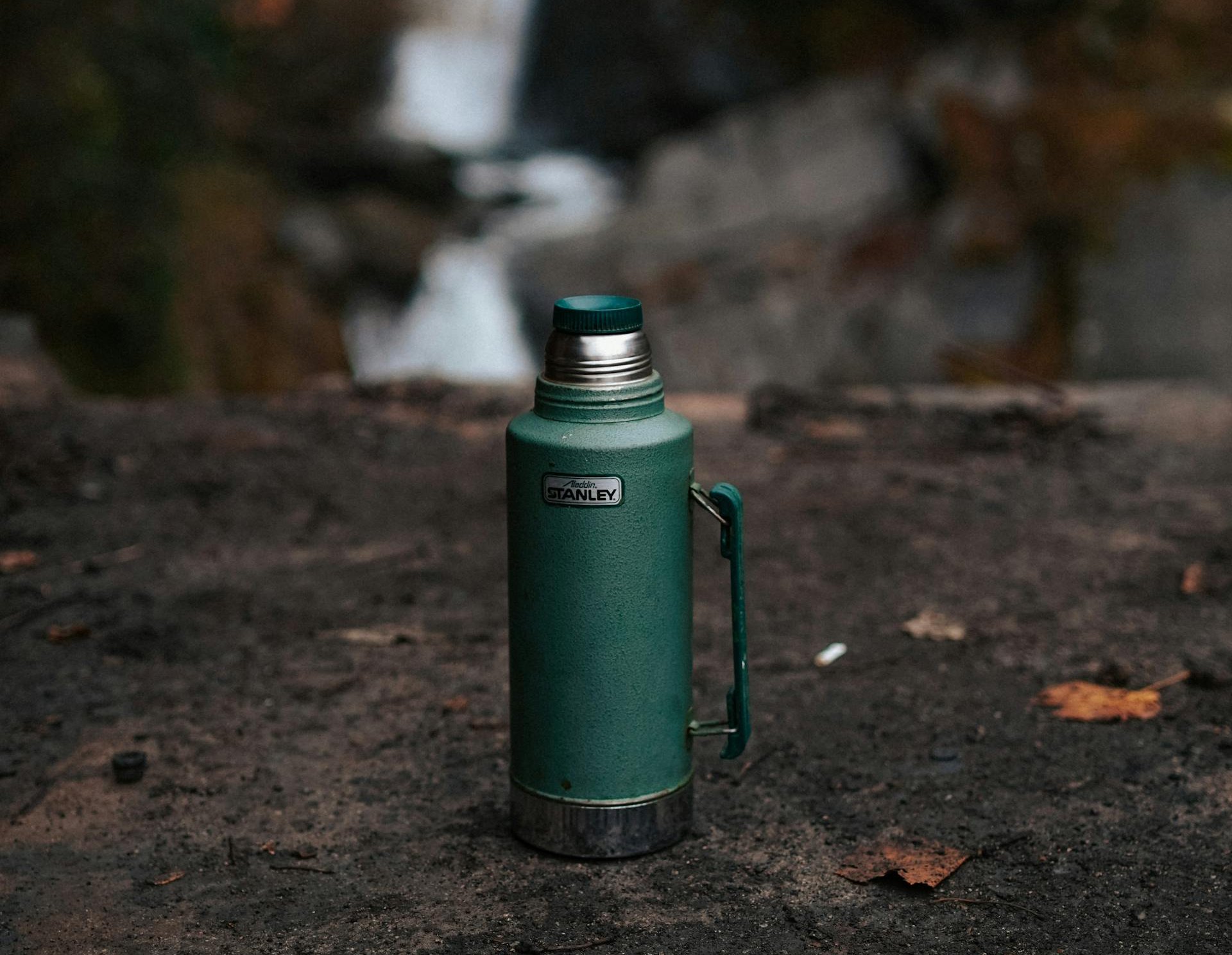 Close Up Photo of Green Thermos on the Ground