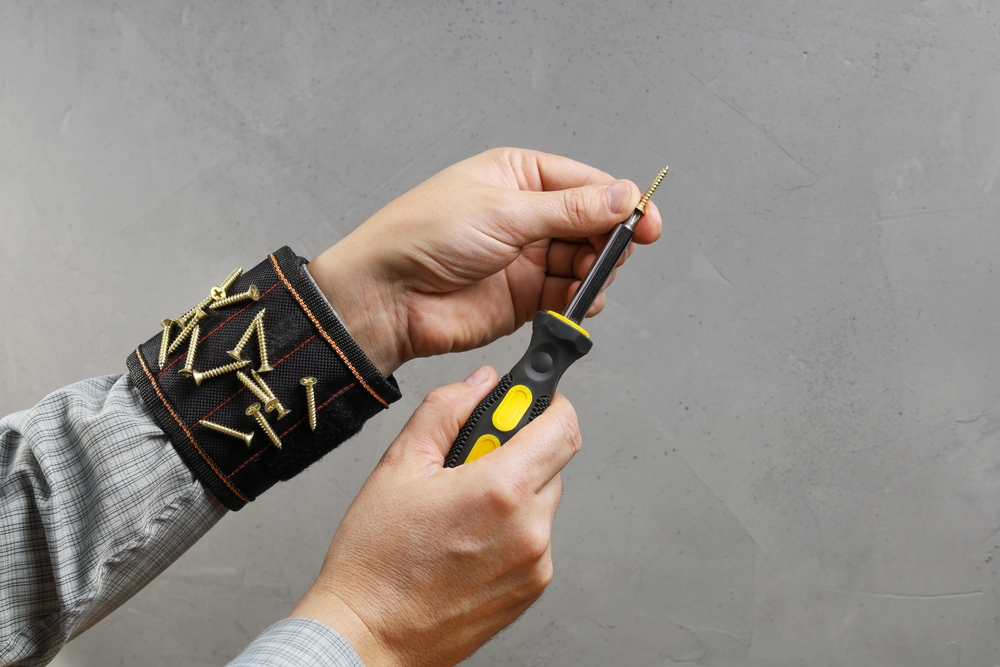 Tools magnetic bracelet on wrist with screws and screwdriver in person hands