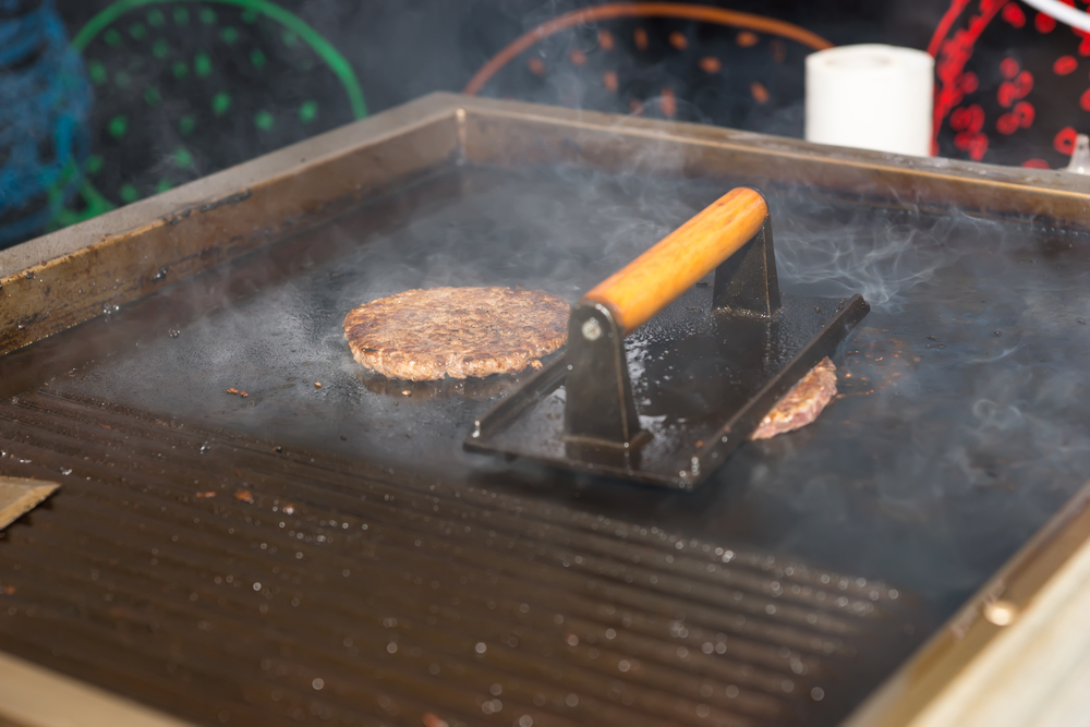 Close Up of Handmade Hamburgers Cooking on Hot Grill Using Press