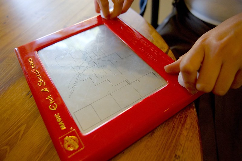 Close Up Photo of a Person playing with Etch-A-Sketch