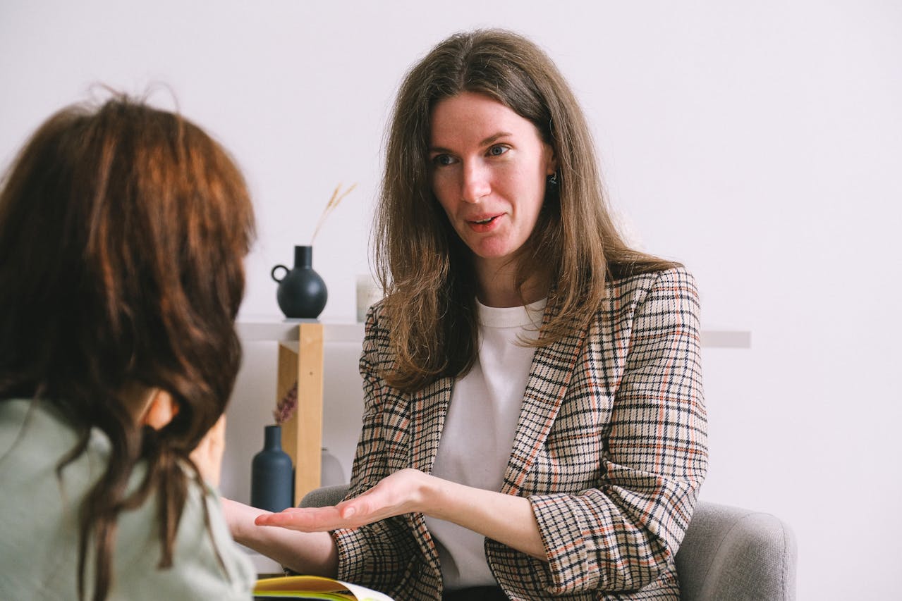 Smiling woman speaking with another female person in light office