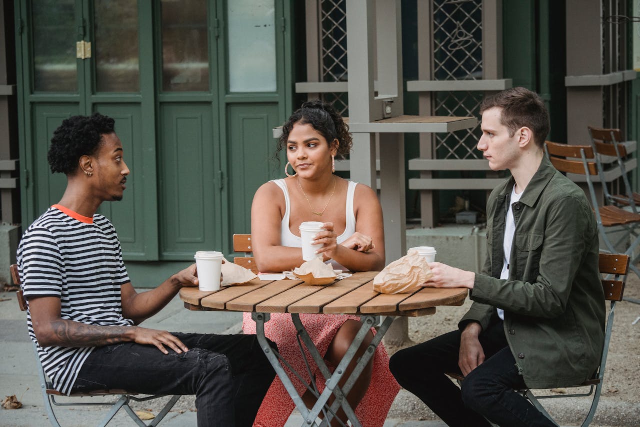 Photo of Young diverse students having coffee break in street cafe