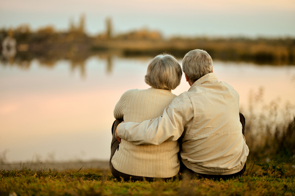 senior couple sitting in summer near lake