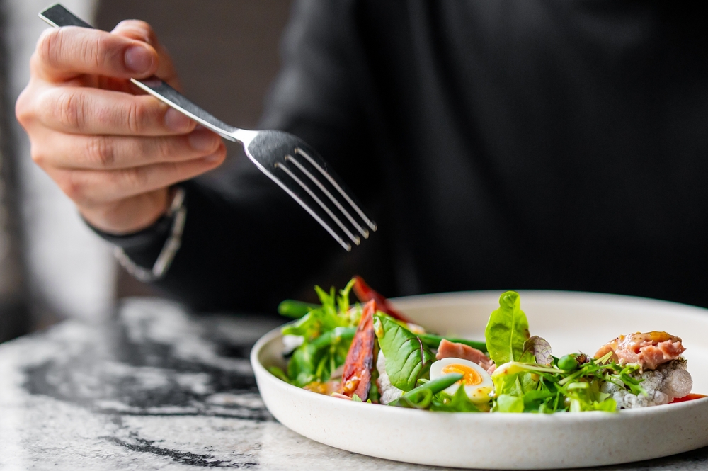 Hand of a man with fork eat Salad