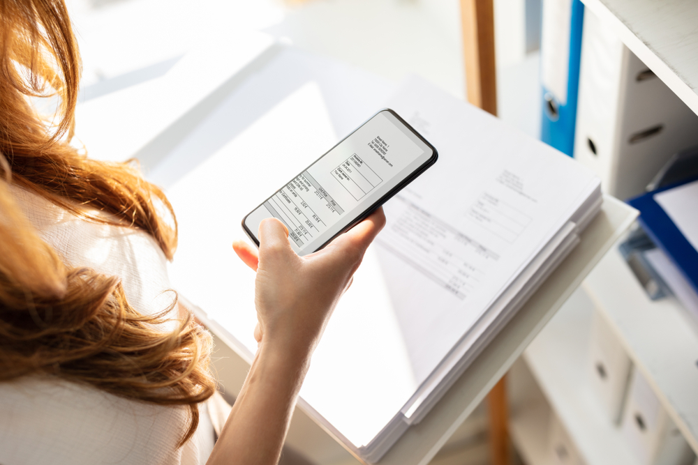 Young Businesswoman Taking Photograph Of Invoice