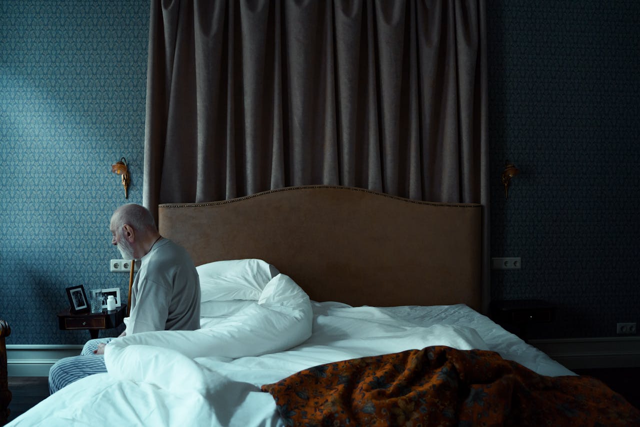 Photo of an Elderly Man Sitting on a Bed
