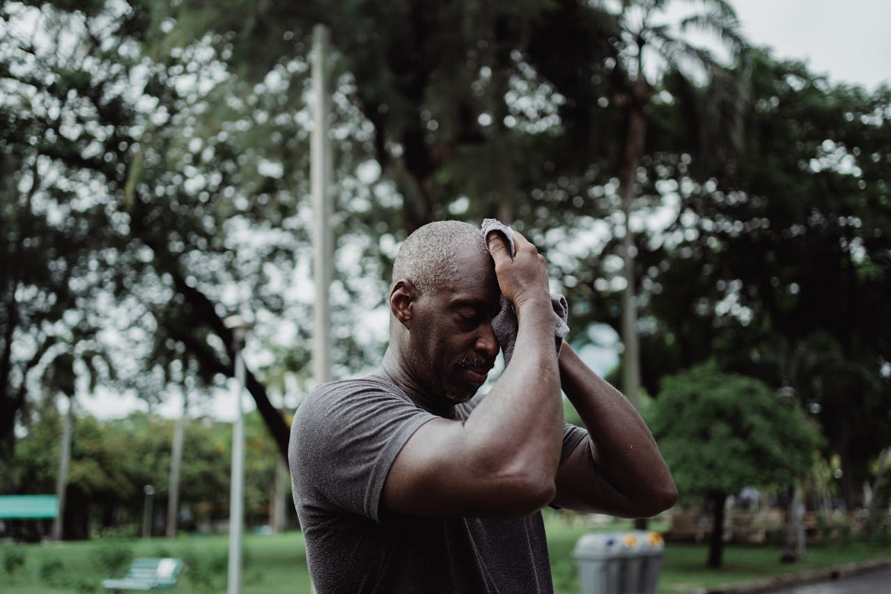 Man in Gray Shirt Wiping His Face With Face Towel