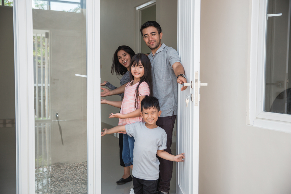 happy family with kids open their house door welcoming