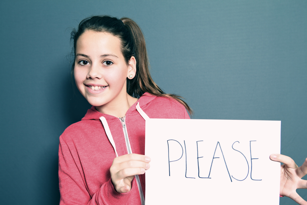 Cute little girl holding up a sheet of white paper