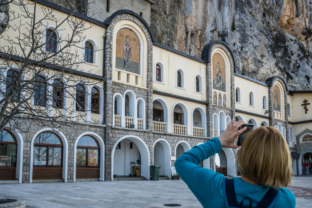 kid taking pictures of the famous landmark Ostrog