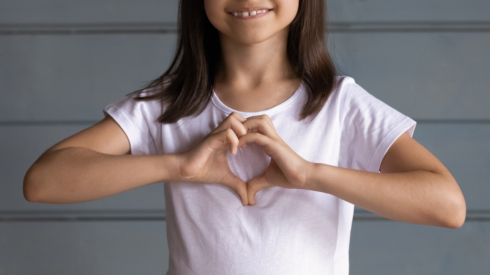 little girl showing heart gesture