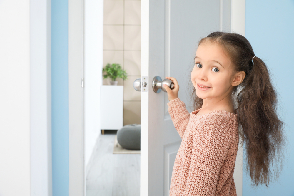Cute little girl opening door in room