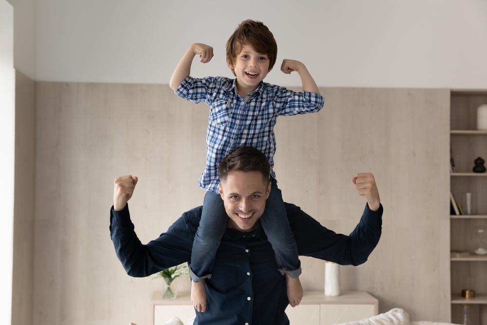 Cheerful little boy riding on happy dads neck