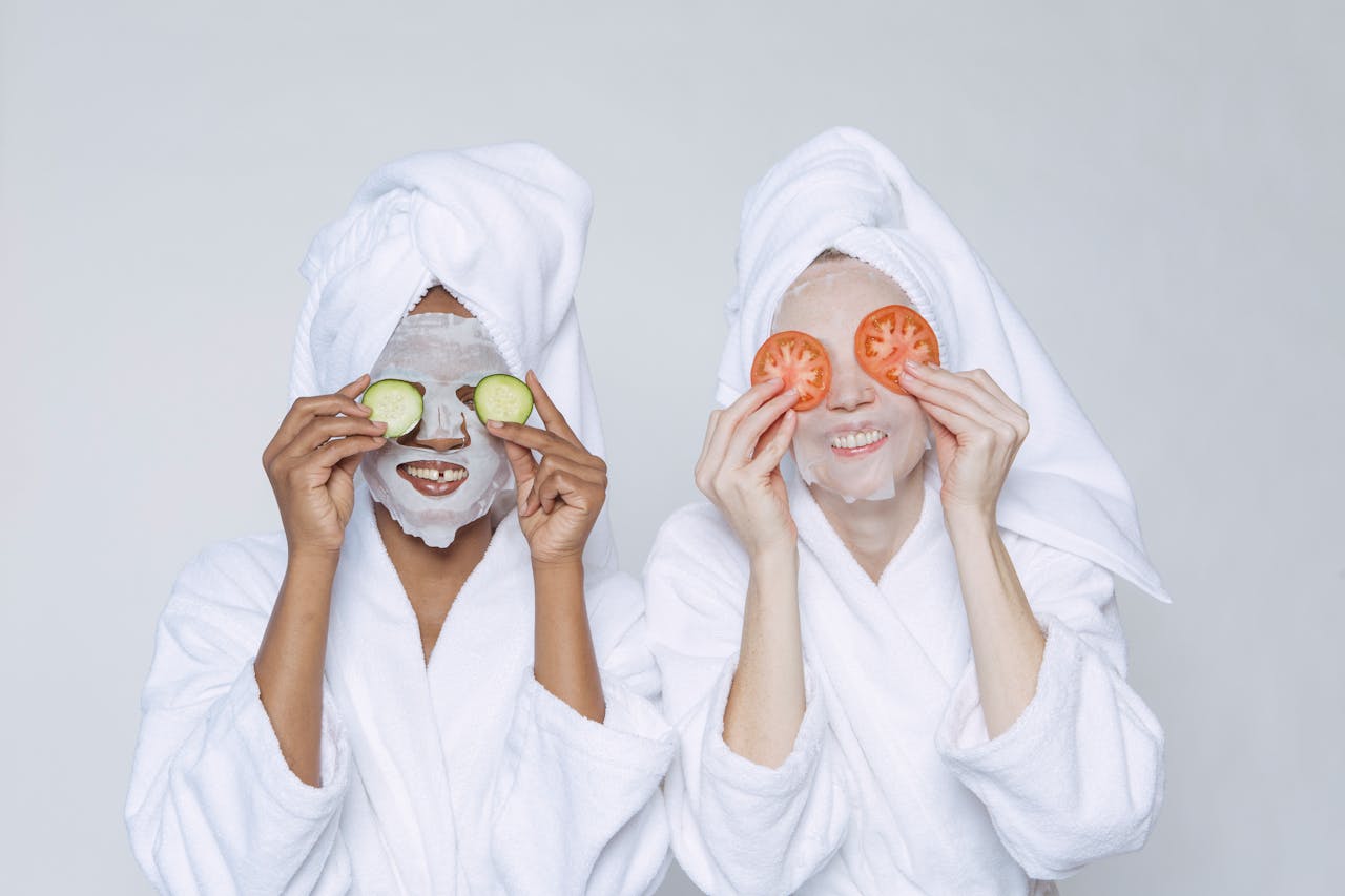 multiethnic women applying cucumber and tomatoes on eyes
