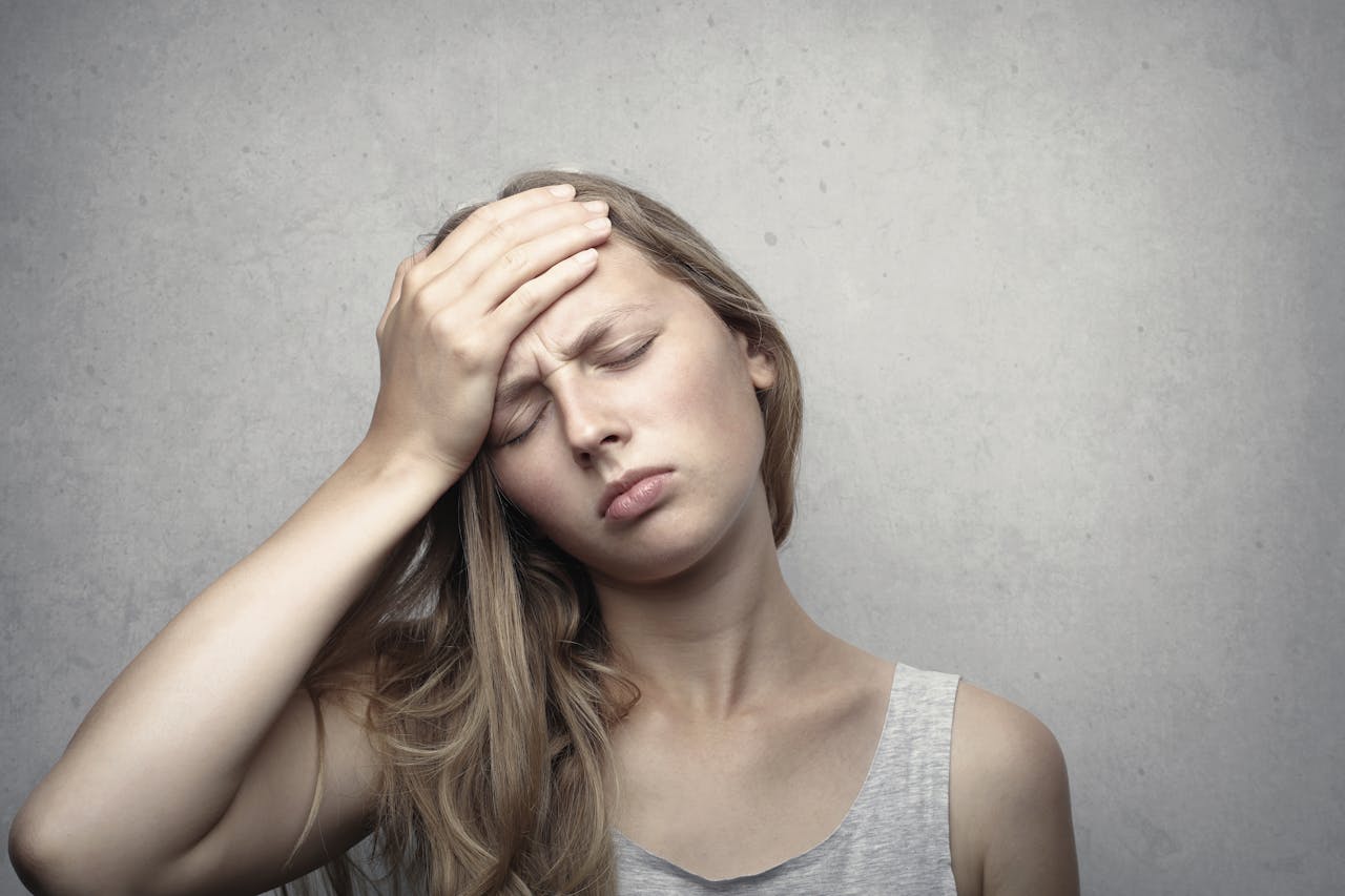 Close Up Photo of Woman in Gray Tank Top holding her forehead