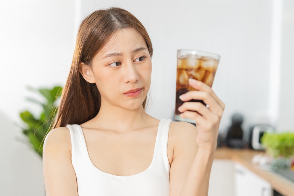 Avoid, limits sweet sugar, choose asian young woman, girl holding, looking at a glass of cold cola soft drink soda