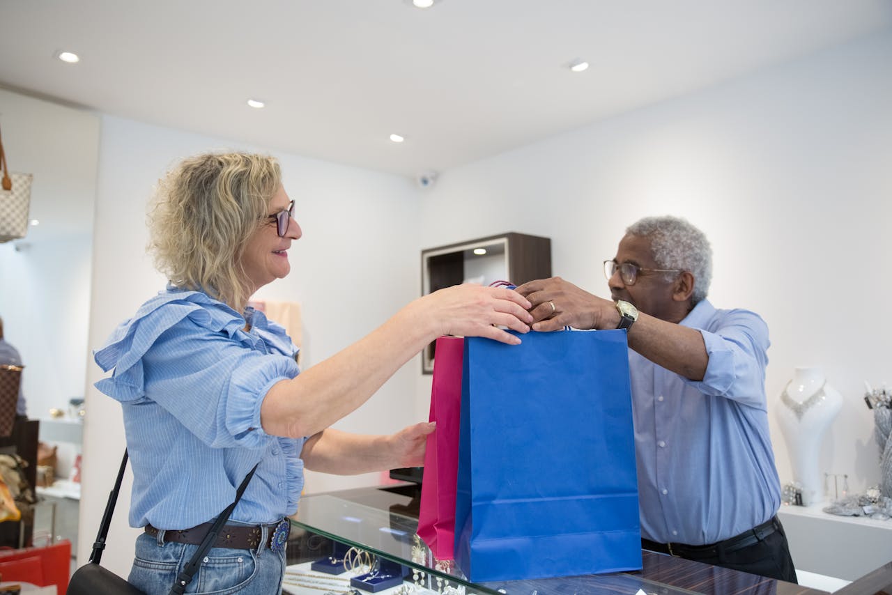 Sales Person Passing Shopping Bags to Customer in a Store
