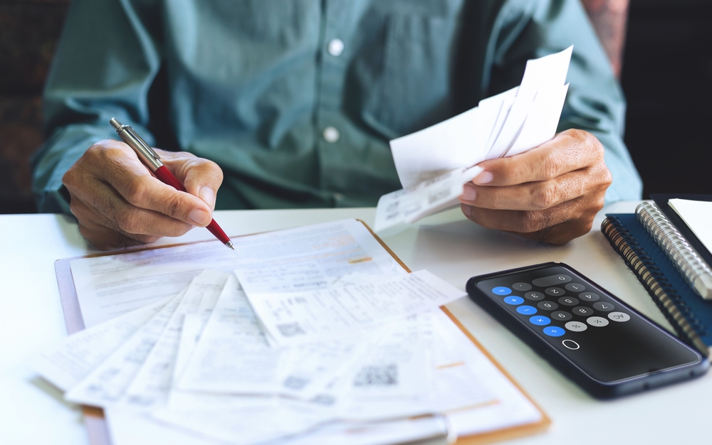 Portrait Photo of Man using smartphone calculating receipt payment, monthly expenses