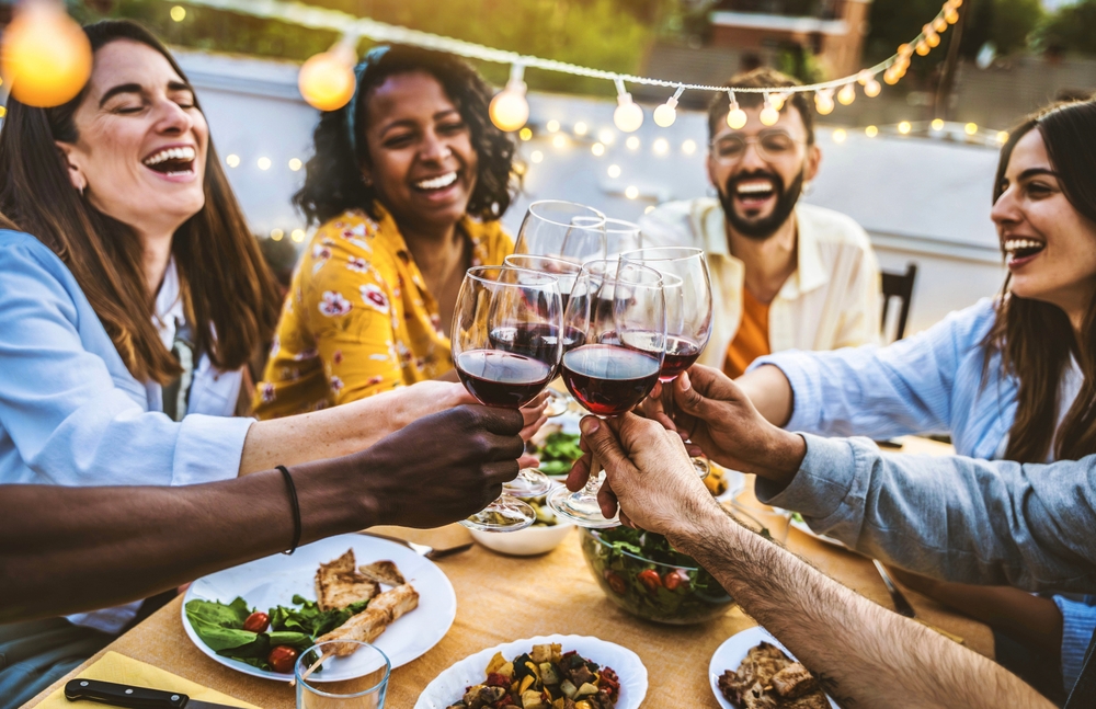 People toasting red wine glasses on rooftop dinner party