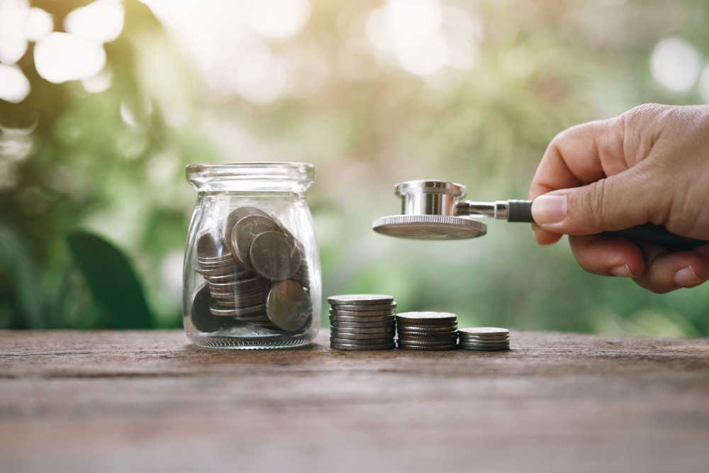 money on table, hand holding stethoscope