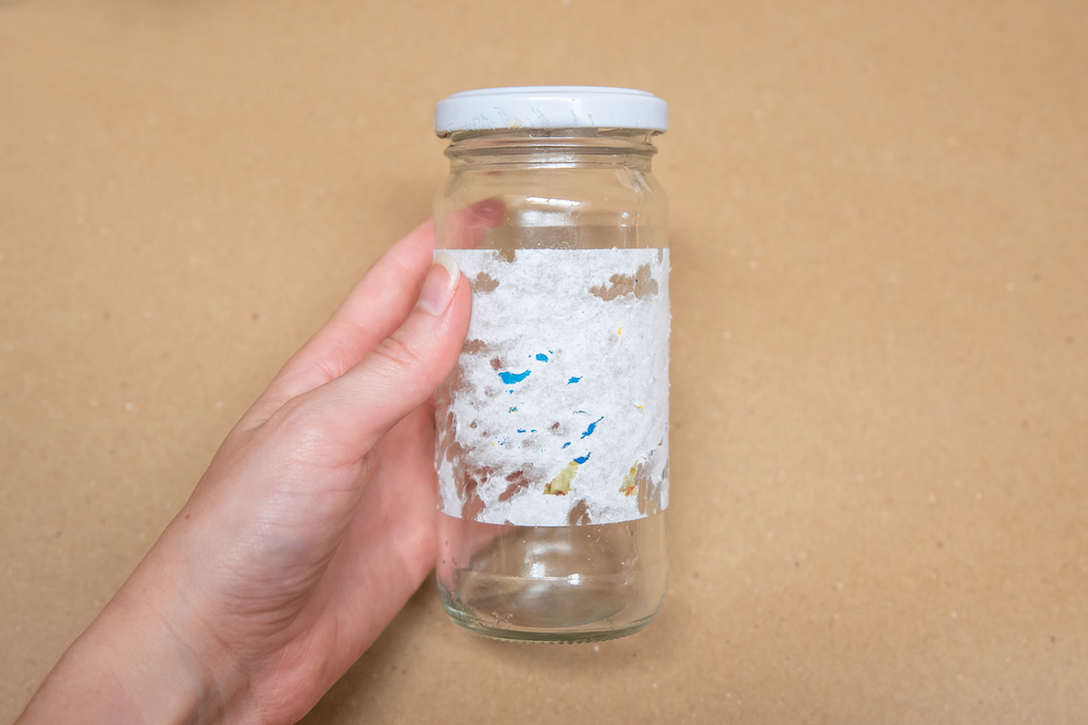 Close Up Photo of person holding a glass jar with sticky label