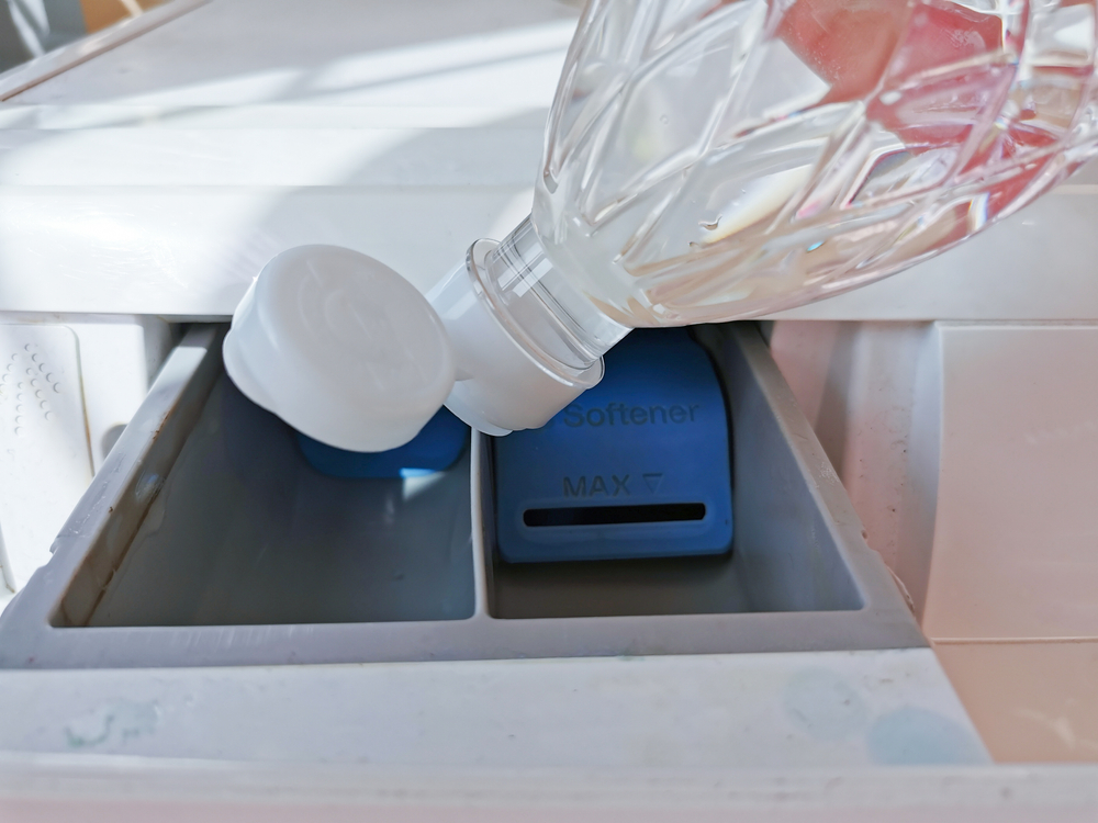 Close up hand pouring the vinegar into the front-loading drawer