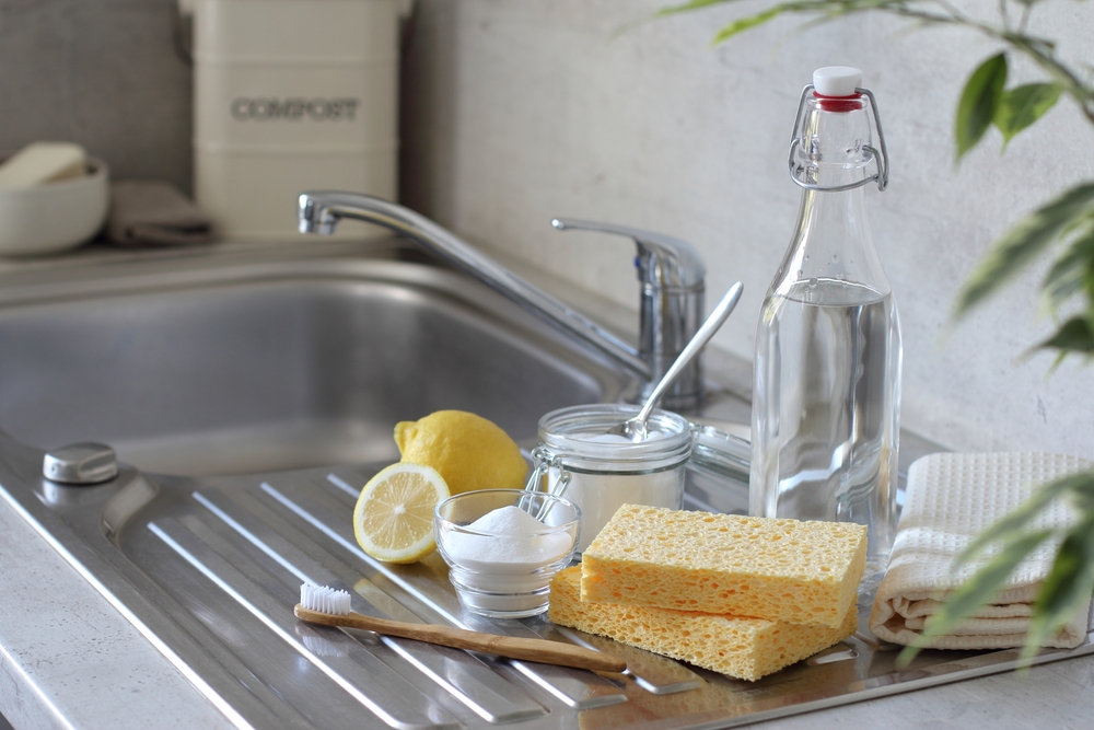 Vinegar and baking soda, lemon, natural sponge, toothbrush and towels on the kitchen sink