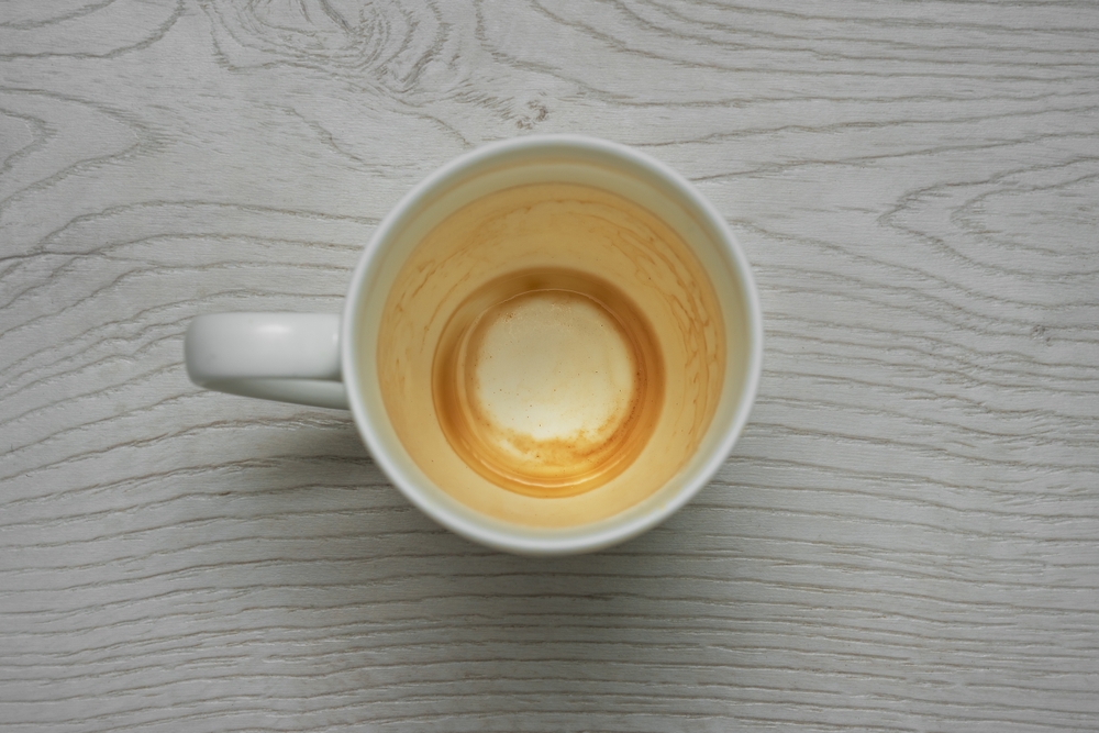 Unwashed mug with stains from cappuccino beverage.
