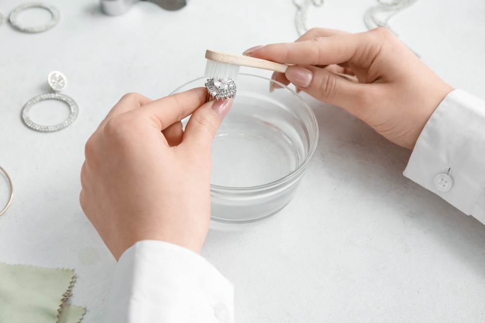 Woman cleaning beautiful ring with toothbrush