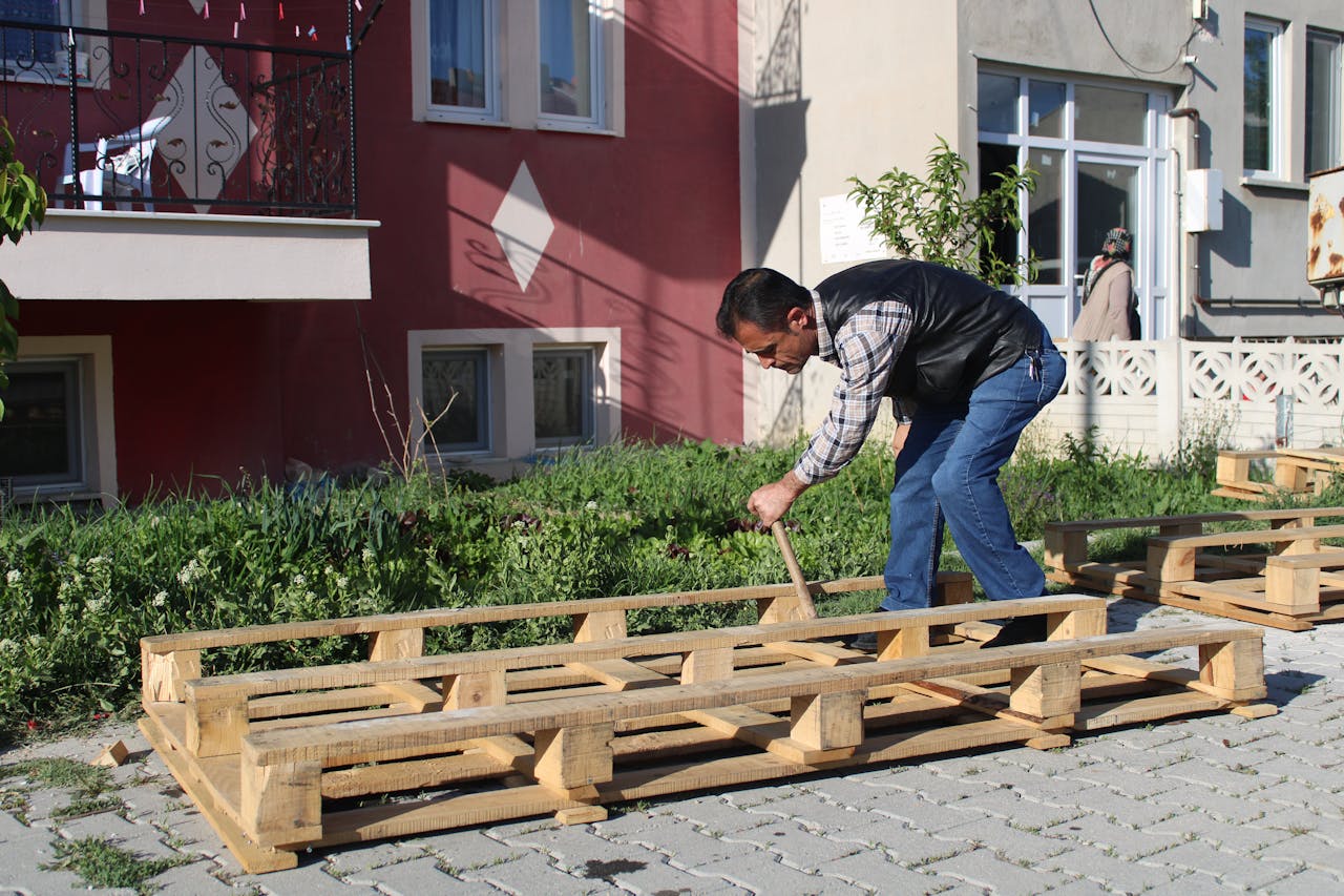Man Working with Wooden Pallet on Pavement