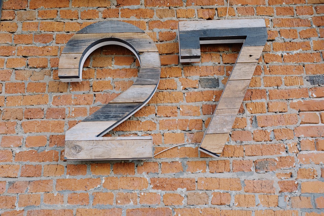 Big wooden number sign hanging on brick wall