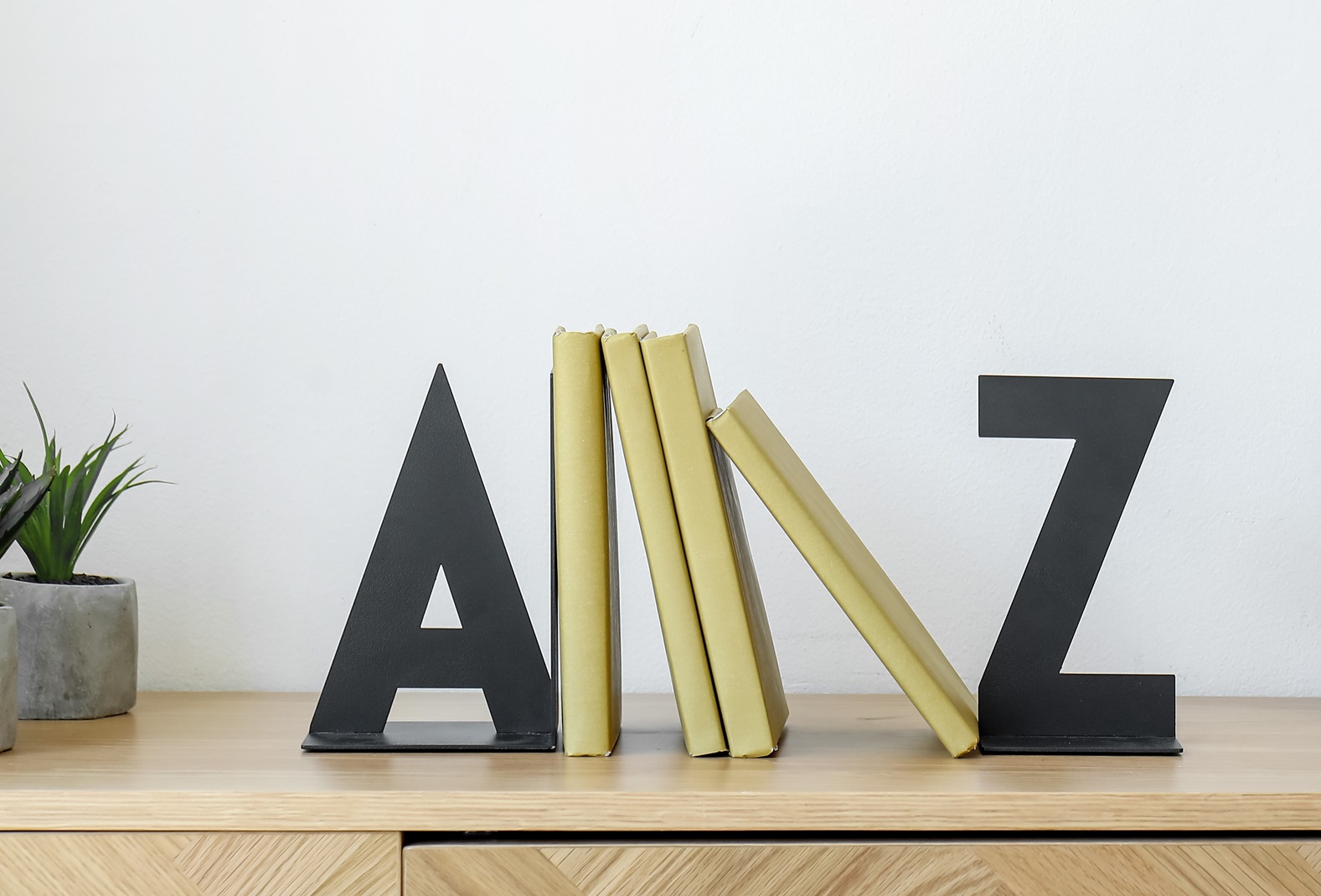 Bookend with frame and candles on chest of drawers near light wall
