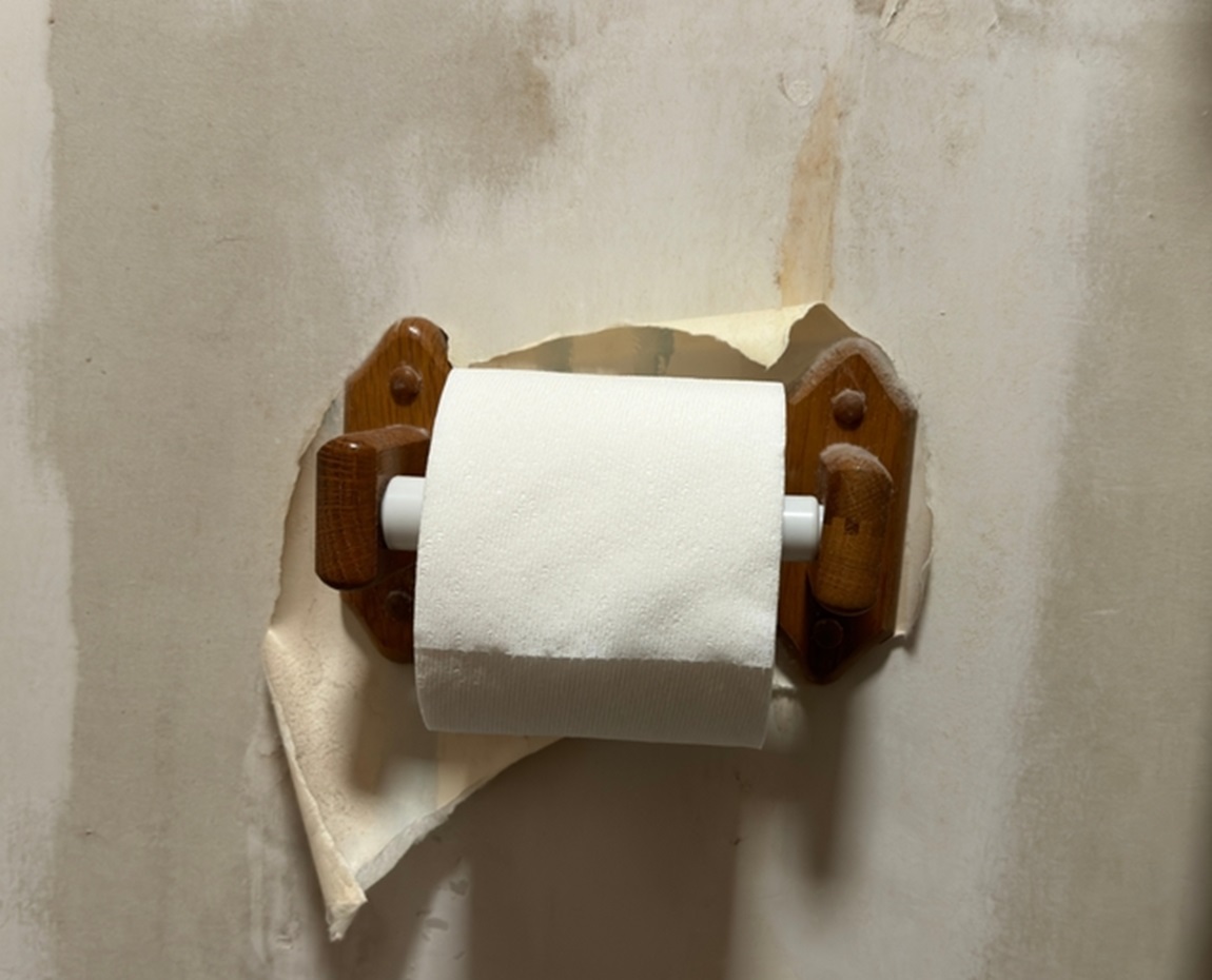 toilet paper on a wooden holder in a bathroom