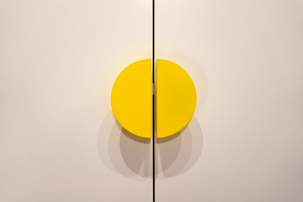 closed white wardrobe with wooden doors and yellow wooden handles