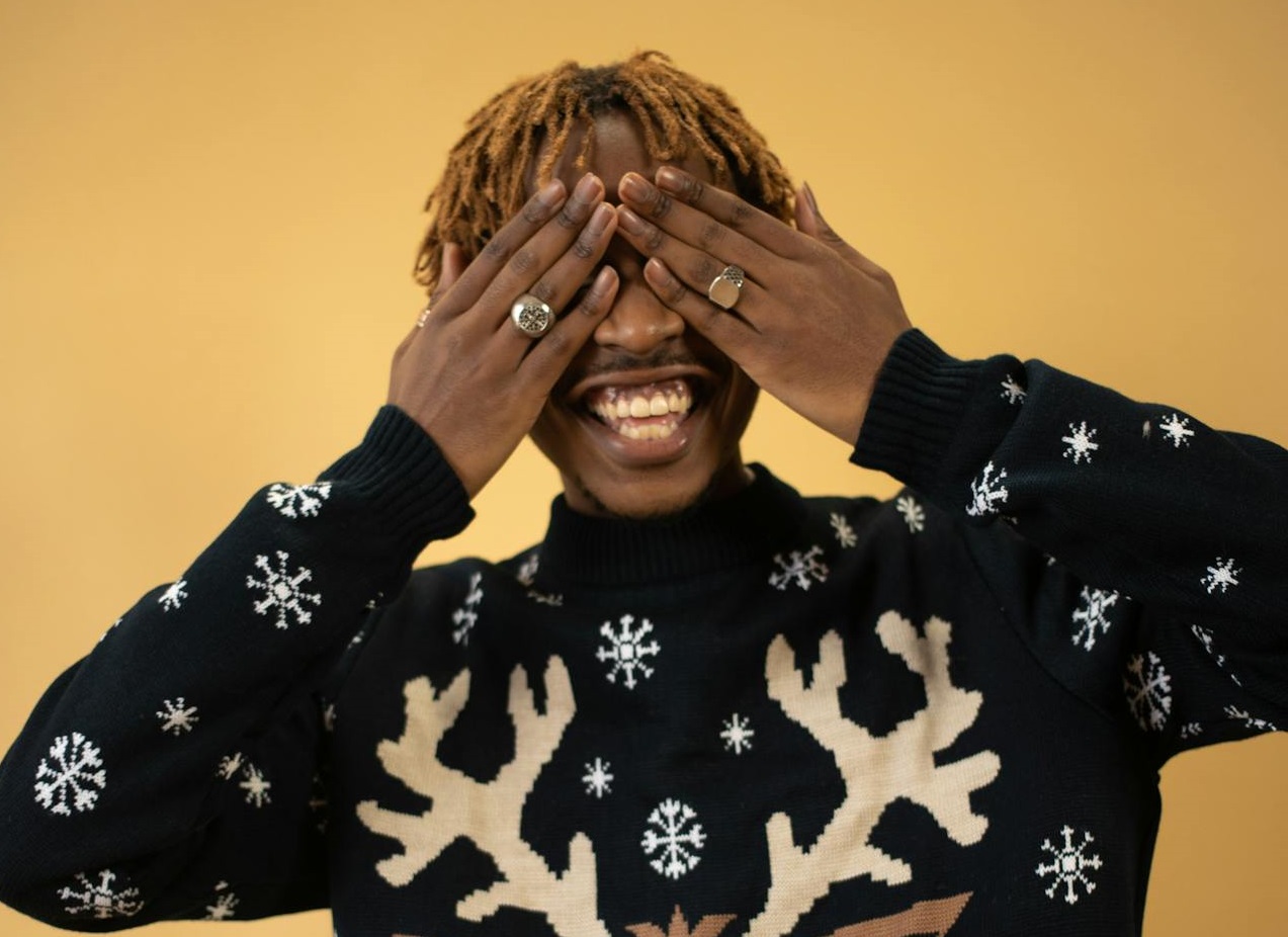 Smiling Man in New Year Sweater Cover Eyes with Hands