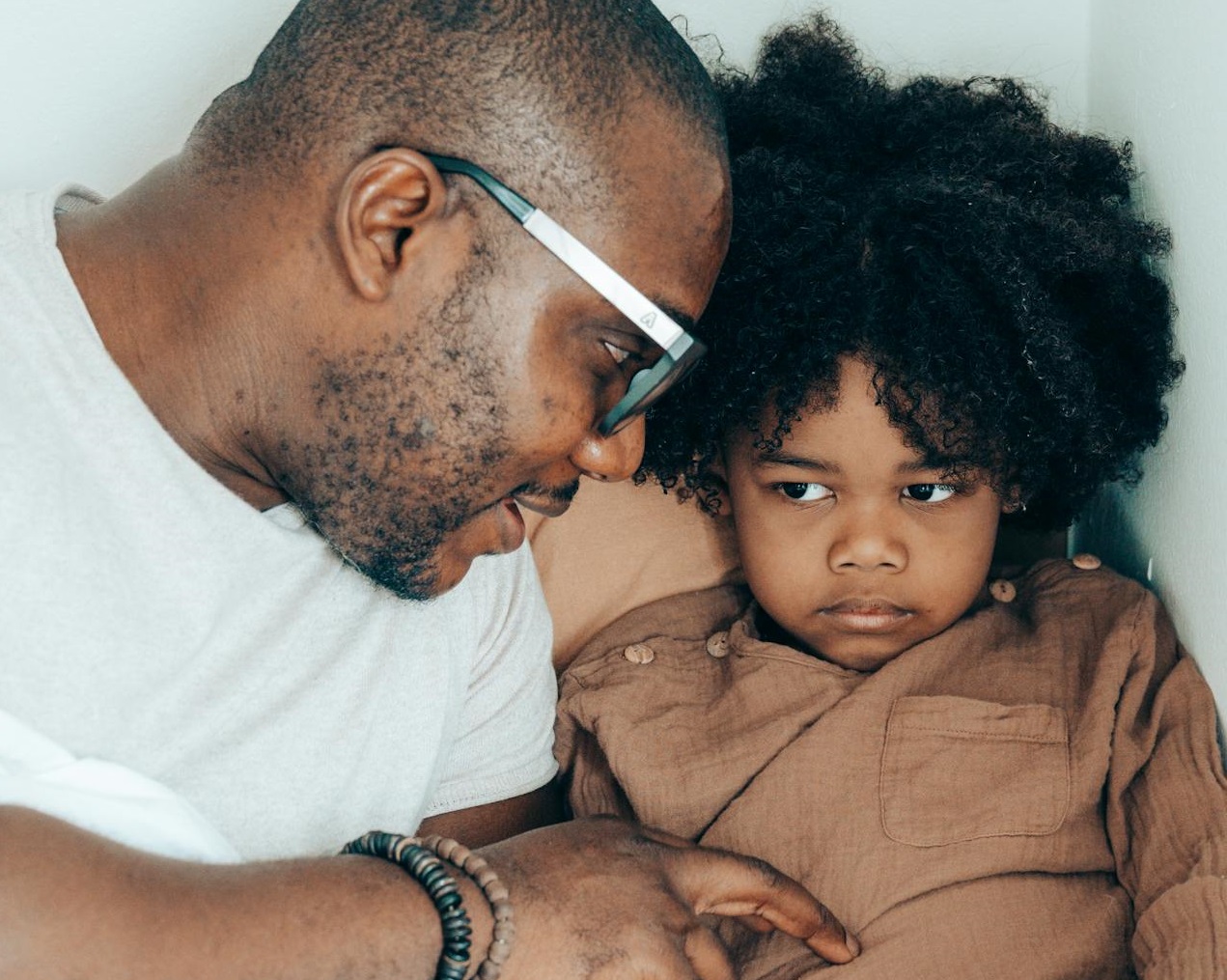 Father resting with cute daughter in bed at home