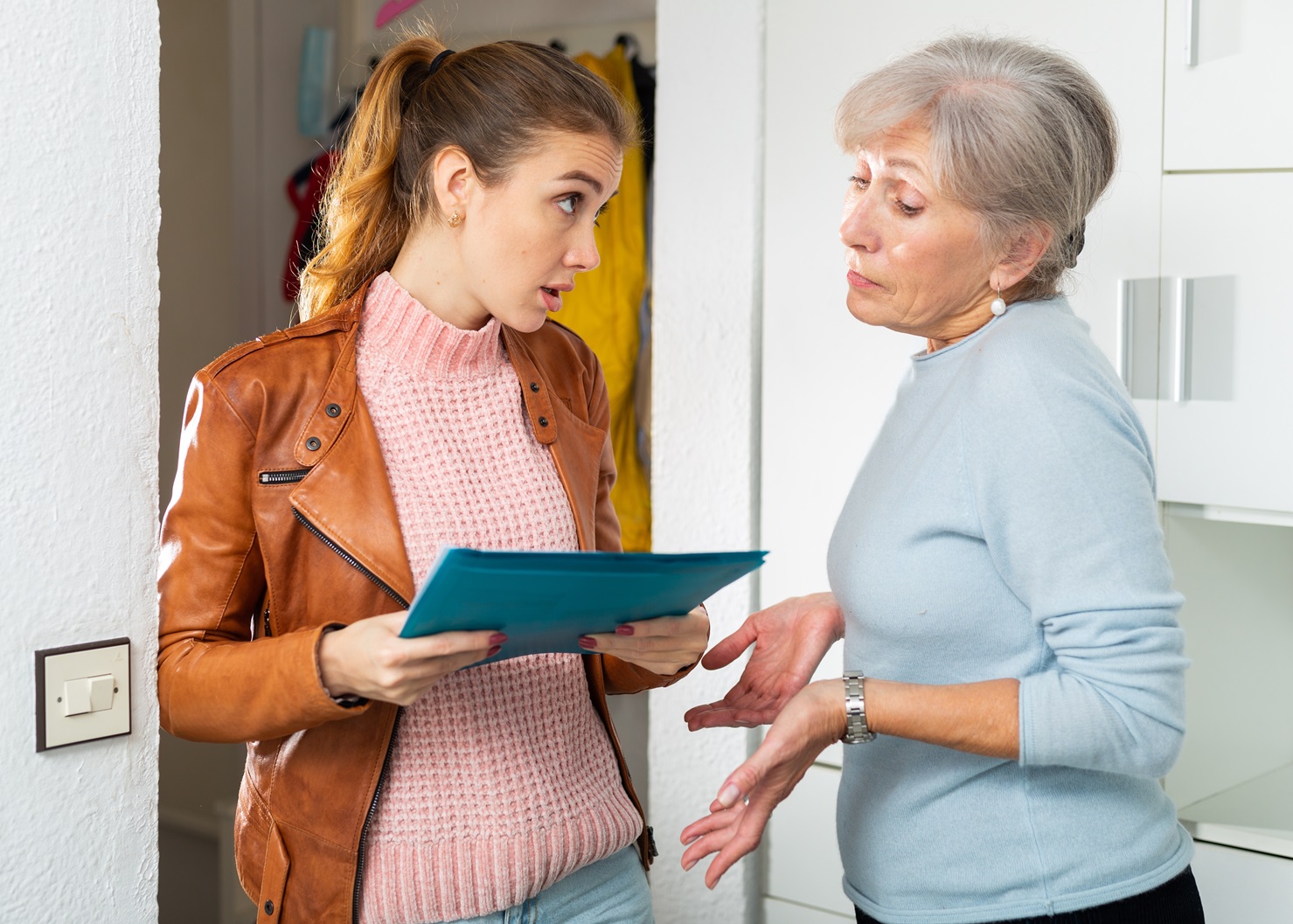 Senior and younger women standing at home and quarreling about breach of rent contract.