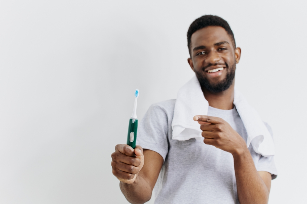 Man promoting dental hygiene with a toothbrush, smiling and pointing at the camera