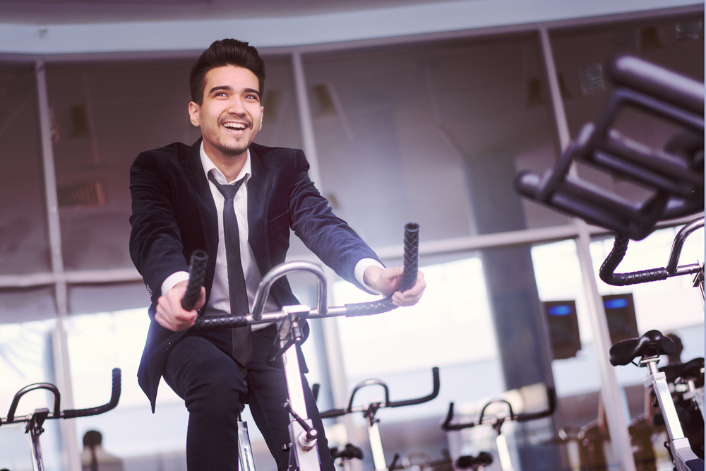 Handsome young man in a black suit, white shirt and tie training in the gym