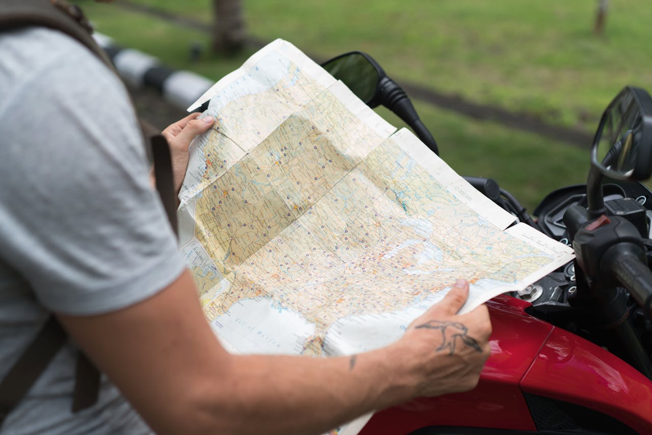 Crop man studying city map sitting on motorbike
