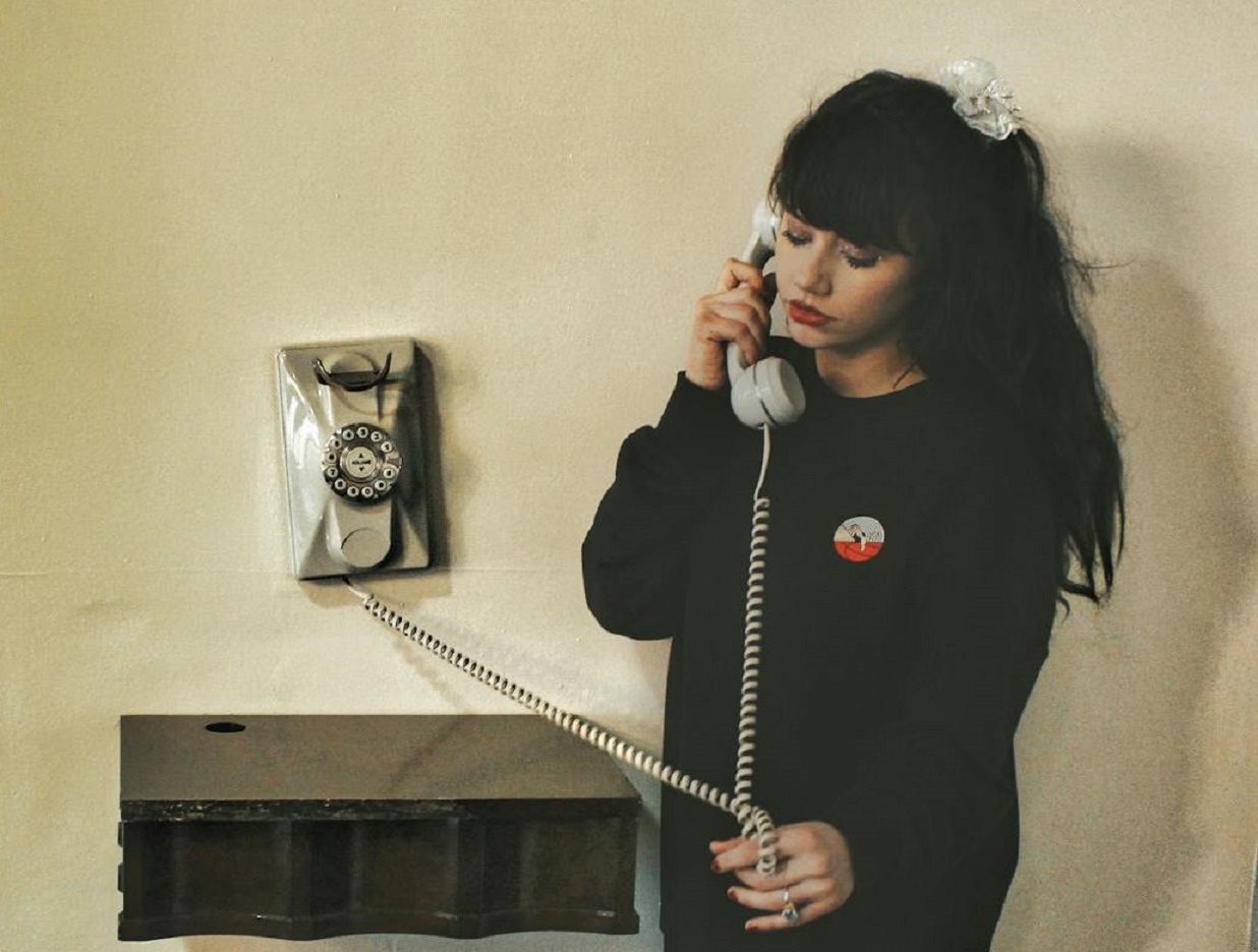 Girl Standing near Wall Talking on Landline Phone