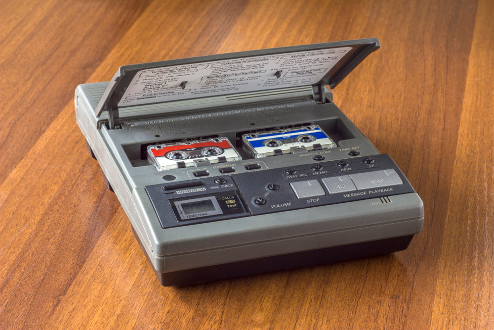 old vintage answering machine with two small tape cassettes on a wooden table surface