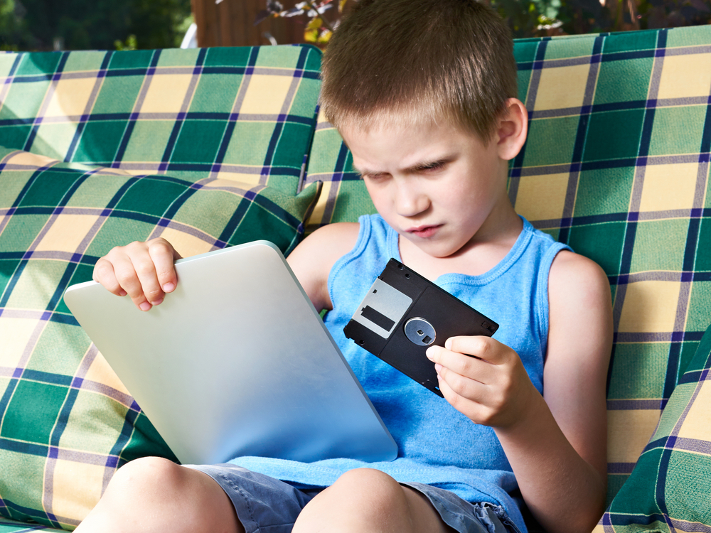 Little boy with floppy disk and tablet pc.