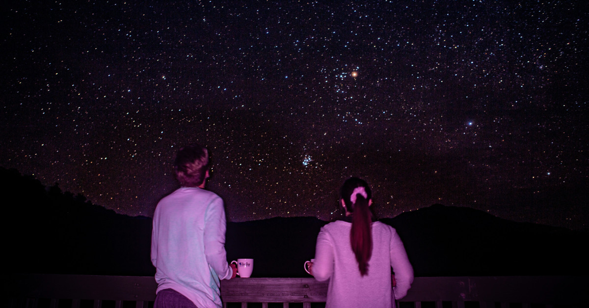 man and woman standing in front of galaxy