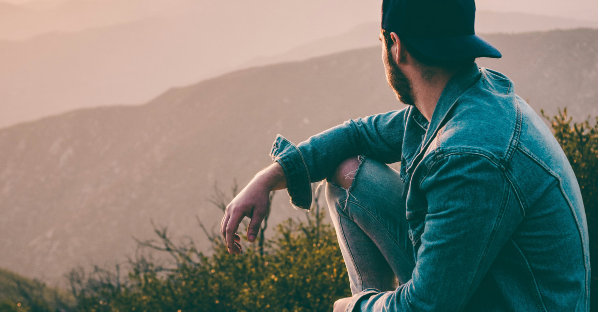 man sitting on gray rock
